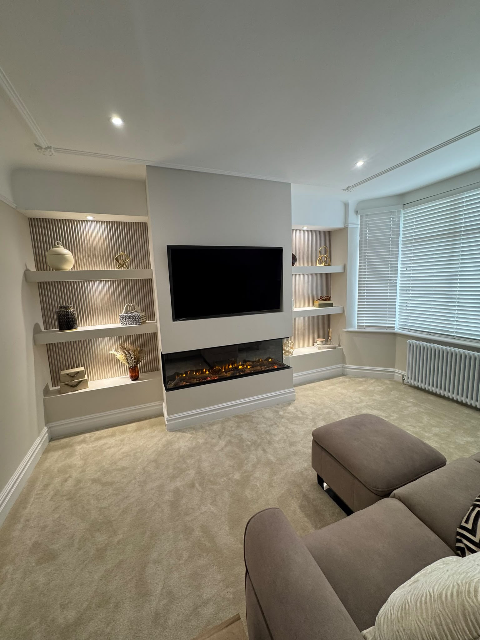 Living room media wall with TV, electric fire and lit display shelves